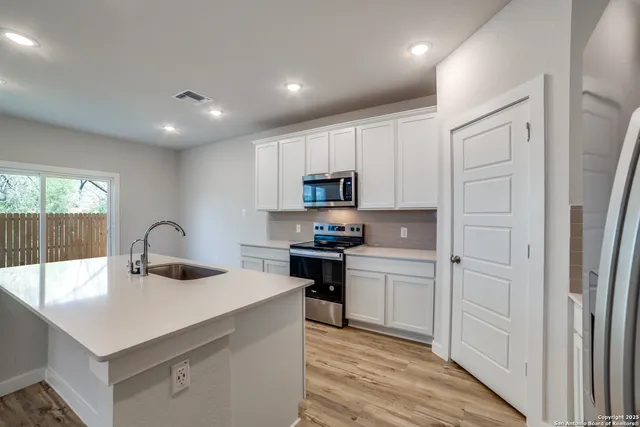 a kitchen with kitchen island a sink appliances cabinets and counter space