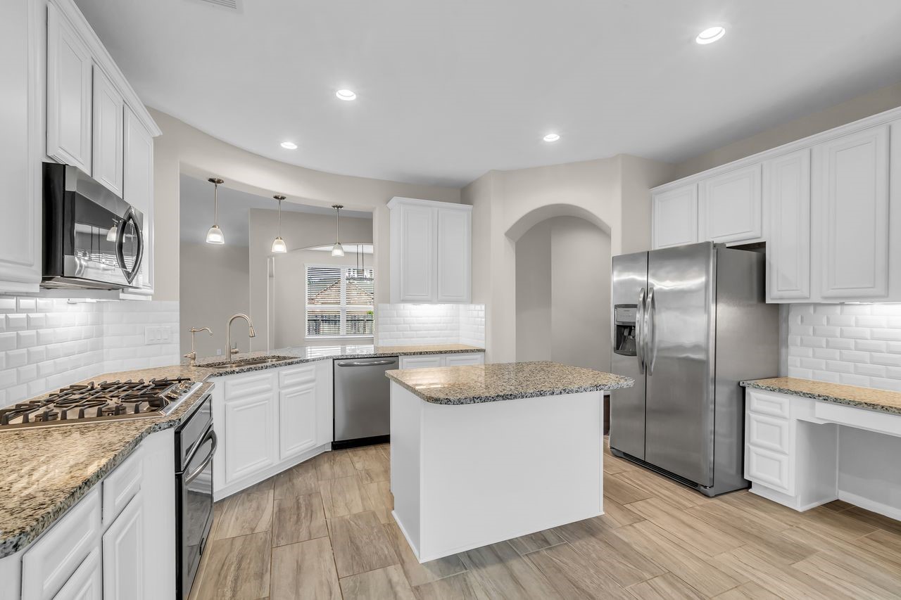 14304 Prospect Park Lane Conroe, TX 77384 - Photo 16 of 38 a large kitchen with stainless steel appliances granite countertop a stove a sink dishwasher a refrigerator and white cabinets with wooden floor