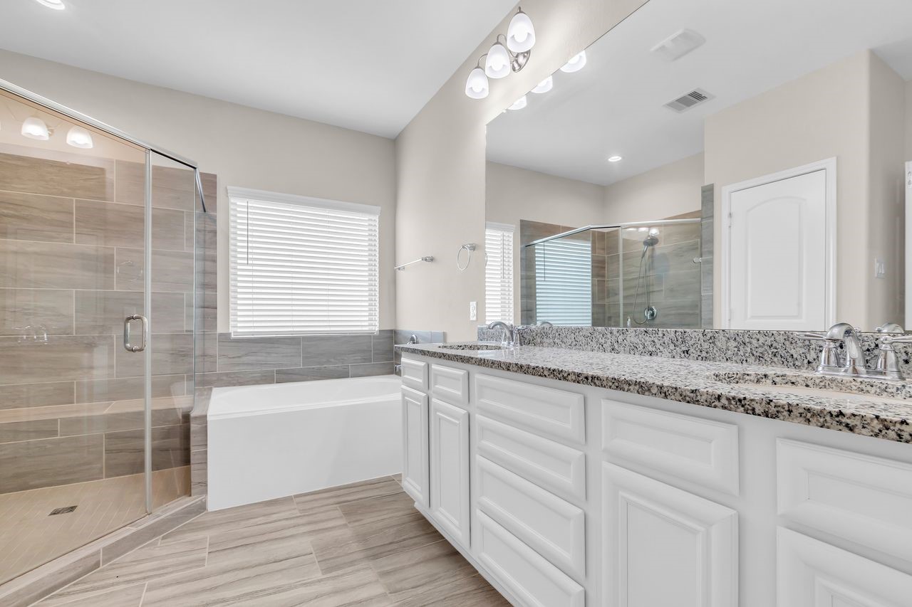 14304 Prospect Park Lane Conroe, TX 77384 - Photo 25 of 38 a bathroom with a granite countertop double vanity sink a mirror and a bathtub