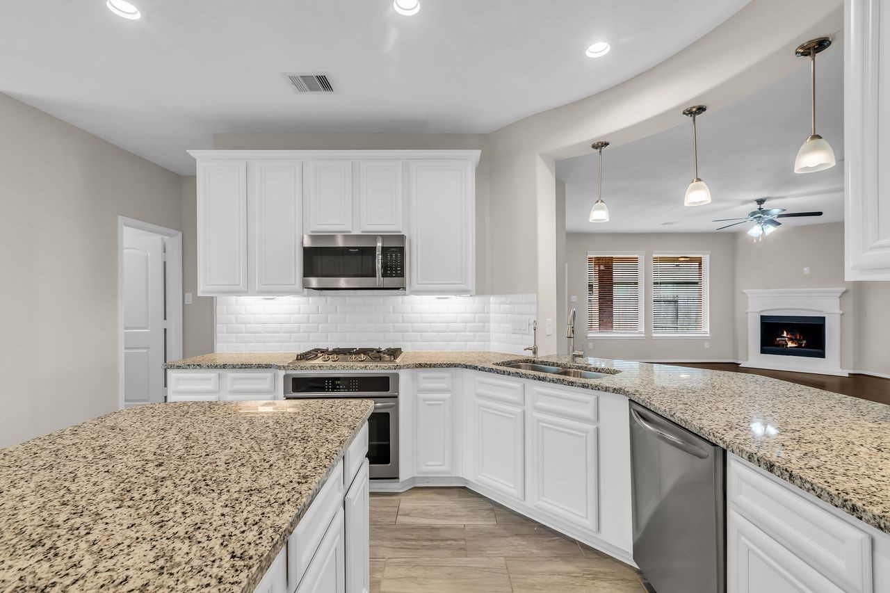 14304 Prospect Park Lane Conroe, TX 77384 - Photo 9 of 38 a kitchen with granite countertop kitchen island sink stove and microwave
