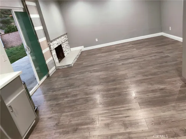 a view of an empty room with wooden floor and a fireplace