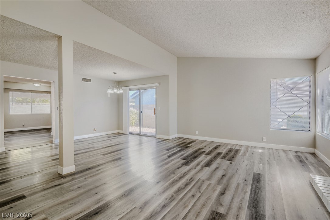 2343 Valleywood Road Henderson, NV 89014 - Photo 15 of 29 Natural light floods through multiple windows, illuminating the durable plank flooring throughout this inviting living space.