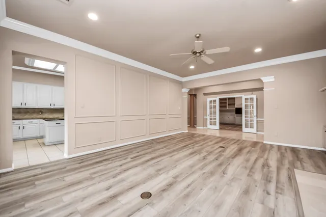 an empty room with wooden floor cabinet and windows