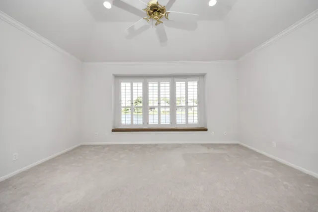 an empty room with a chandelier fan and windows