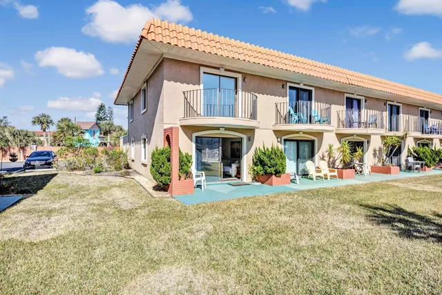 a view of a white house with large windows and a table and chairs in porch