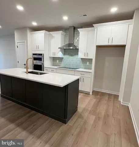 a kitchen with kitchen island a sink a stove a refrigerator and white cabinets