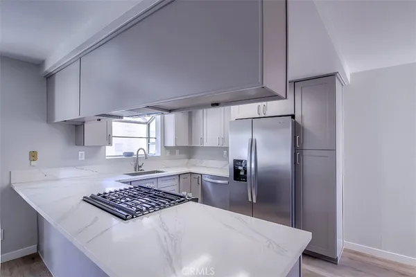 a kitchen with kitchen island a counter top space a sink stainless steel appliances and cabinets