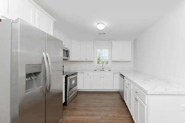 a kitchen with a sink a refrigerator and white cabinets