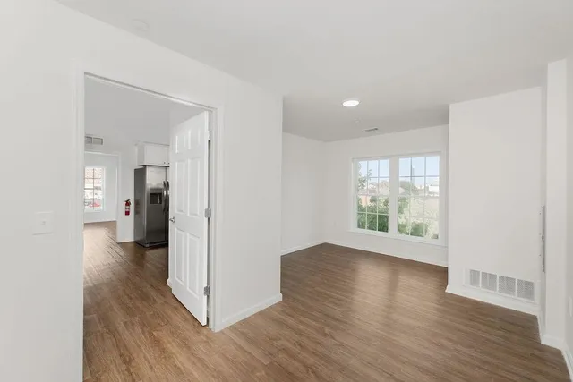 a view of a hallway with wooden floor and a living room