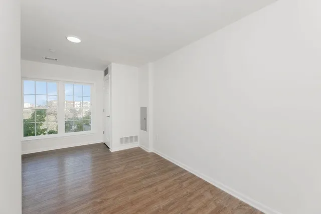 an empty room with wooden floor and windows