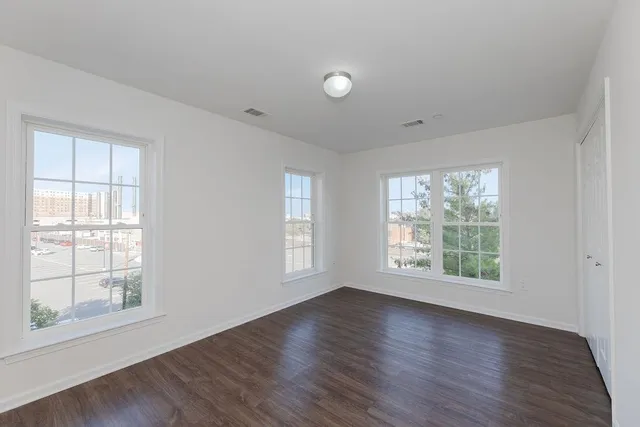 an empty room with wooden floor and windows
