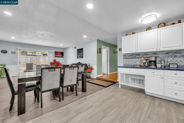 a kitchen with stainless steel appliances granite countertop a stove a sink dishwasher and white cabinets with wooden floor