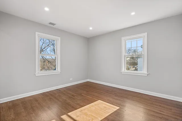 a view of an empty room with a window and wooden floor