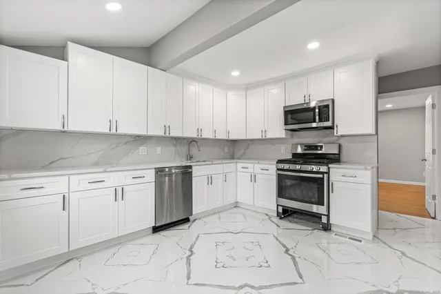 a kitchen with stainless steel appliances granite countertop a stove a sink and a refrigerator