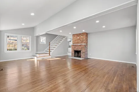 an empty room with wooden floor and fireplace