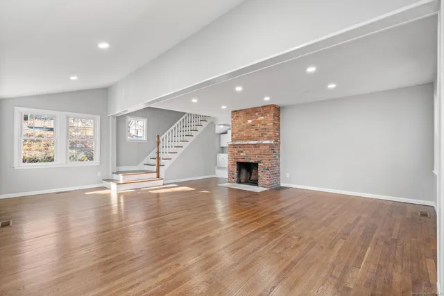 an empty room with wooden floor and fireplace