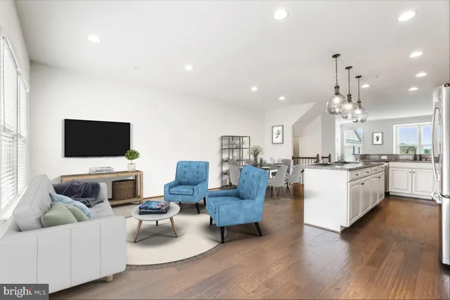 a living room with furniture a flat screen tv and kitchen view