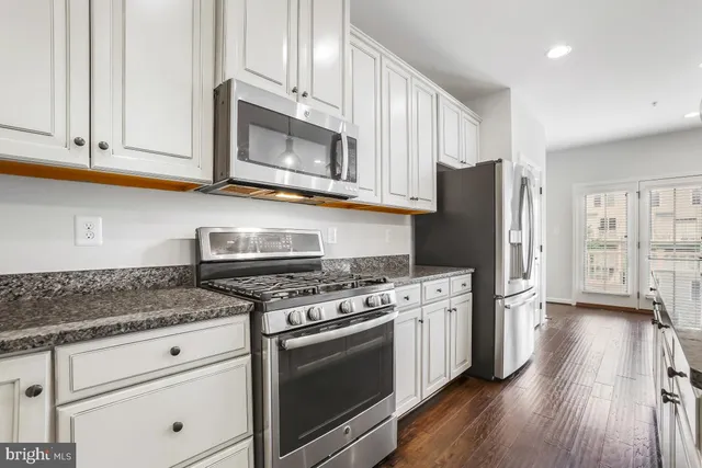 a large kitchen with stainless steel appliances granite countertop a lot of counter space and wooden floor