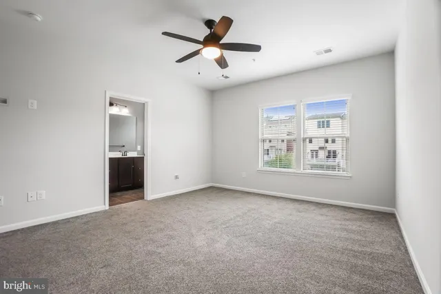 an empty room with ceiling fan and window