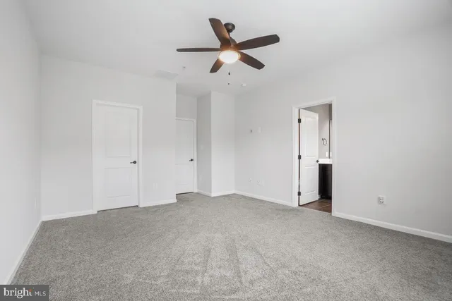 an empty room with chandelier fan and windows