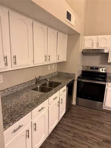 a kitchen with granite countertop a stove sink and cabinets