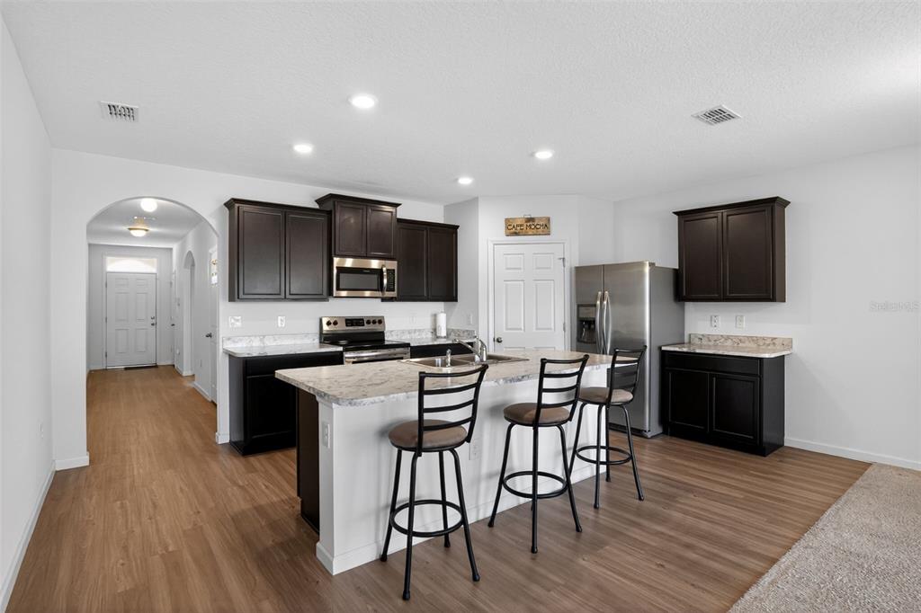 1100 Newton Circle Rockledge, FL 32955 - Photo 7 of 25 a kitchen with stainless steel appliances a stove top oven a sink dishwasher a refrigerator and a dining table with wooden floor