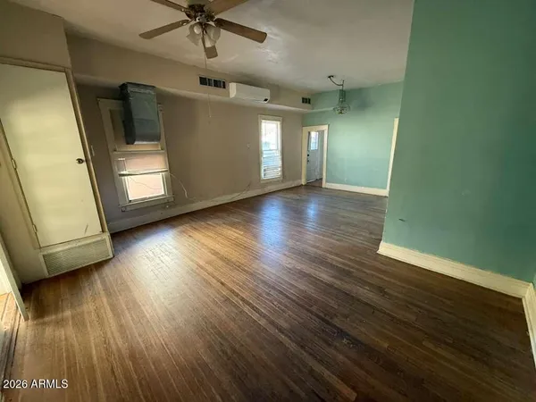 a view of empty room with wooden floor and fan