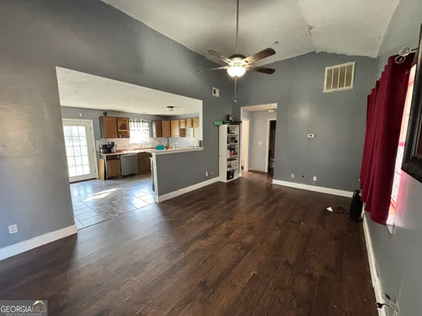 a view of a living room a kitchen with furniture and wooden floor