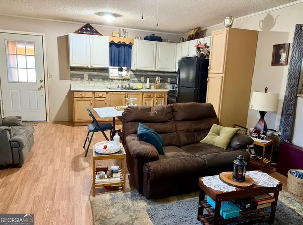 a living room with stainless steel appliances furniture and a wooden floor