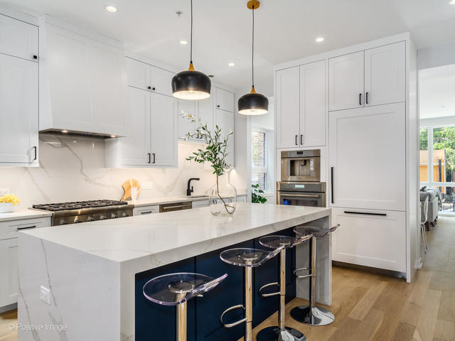 867 North Marshfield Avenue, Unit 1 Chicago, IL 60622 - Photo 2 of 12 a kitchen with stainless steel appliances a sink a stove a refrigerator and chairs with wooden floor