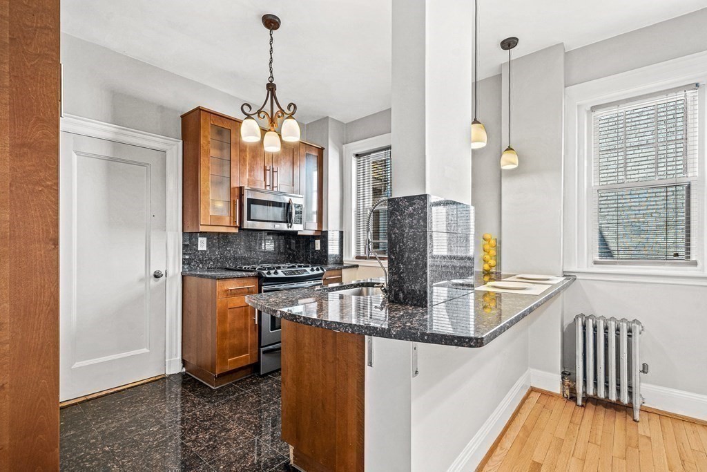 6 Lanark Road, Unit 4 Brookline, MA 02445 - Photo 12 of 23 a kitchen with stainless steel appliances granite countertop a refrigerator a sink dishwasher a stove and a dining table with wooden floor