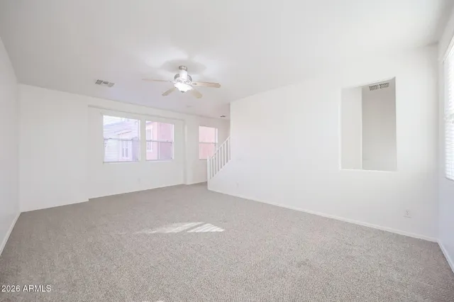 an empty room with windows and chandelier fan