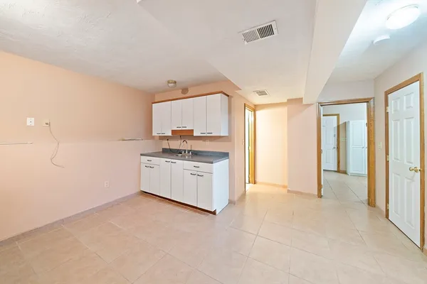 a large white kitchen with a stove a sink dishwasher and a refrigerator with wooden floor