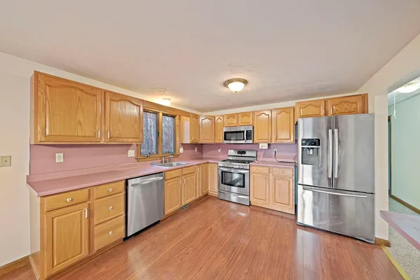 a kitchen with stainless steel appliances granite countertop a refrigerator a stove and a sink with wooden floors