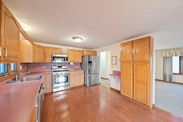 a open kitchen with stainless steel appliances granite countertop a refrigerator stove top oven and sink with wooden floor