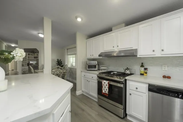 a kitchen with a stove a sink and white cabinets