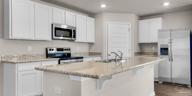 a kitchen with stainless steel appliances granite countertop a sink a stove and a refrigerator