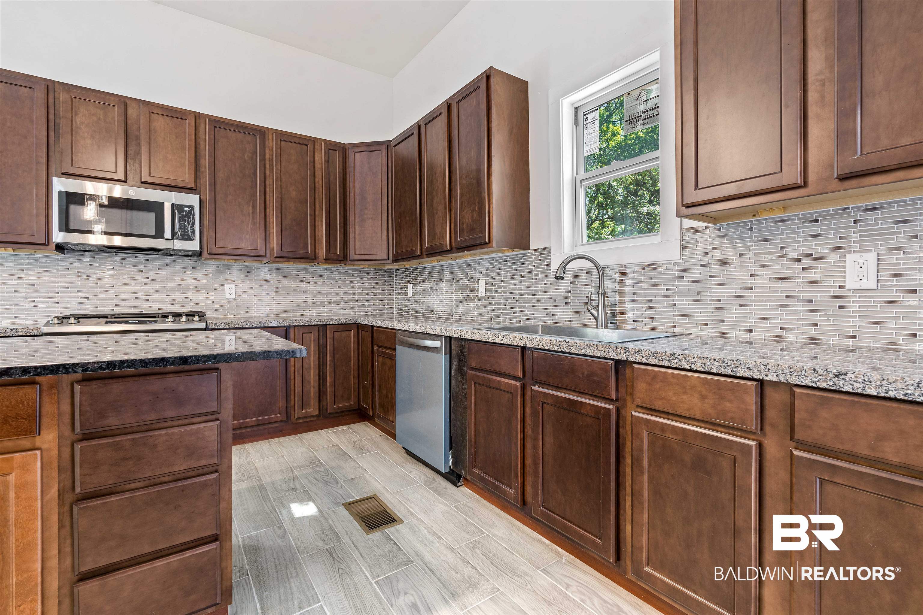 407 East 2nd Street Bay Minette, AL 36507 - Photo 9 of 40 Kitchen featuring backsplash, dark stone counters, stainless steel appliances, wood finish floors, and dark brown cabinetry