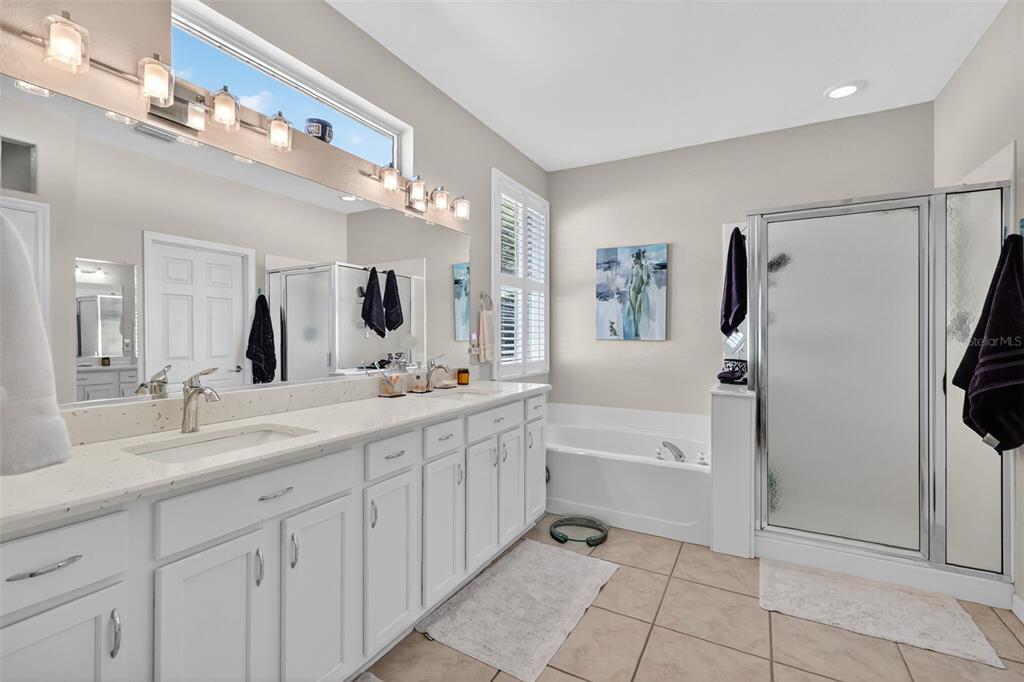 13536 Southeast 97th Terrace Road Summerfield, FL 34491 - Photo 17 of 34 a spacious bathroom with a granite countertop sink a mirror a bathtub and a shower