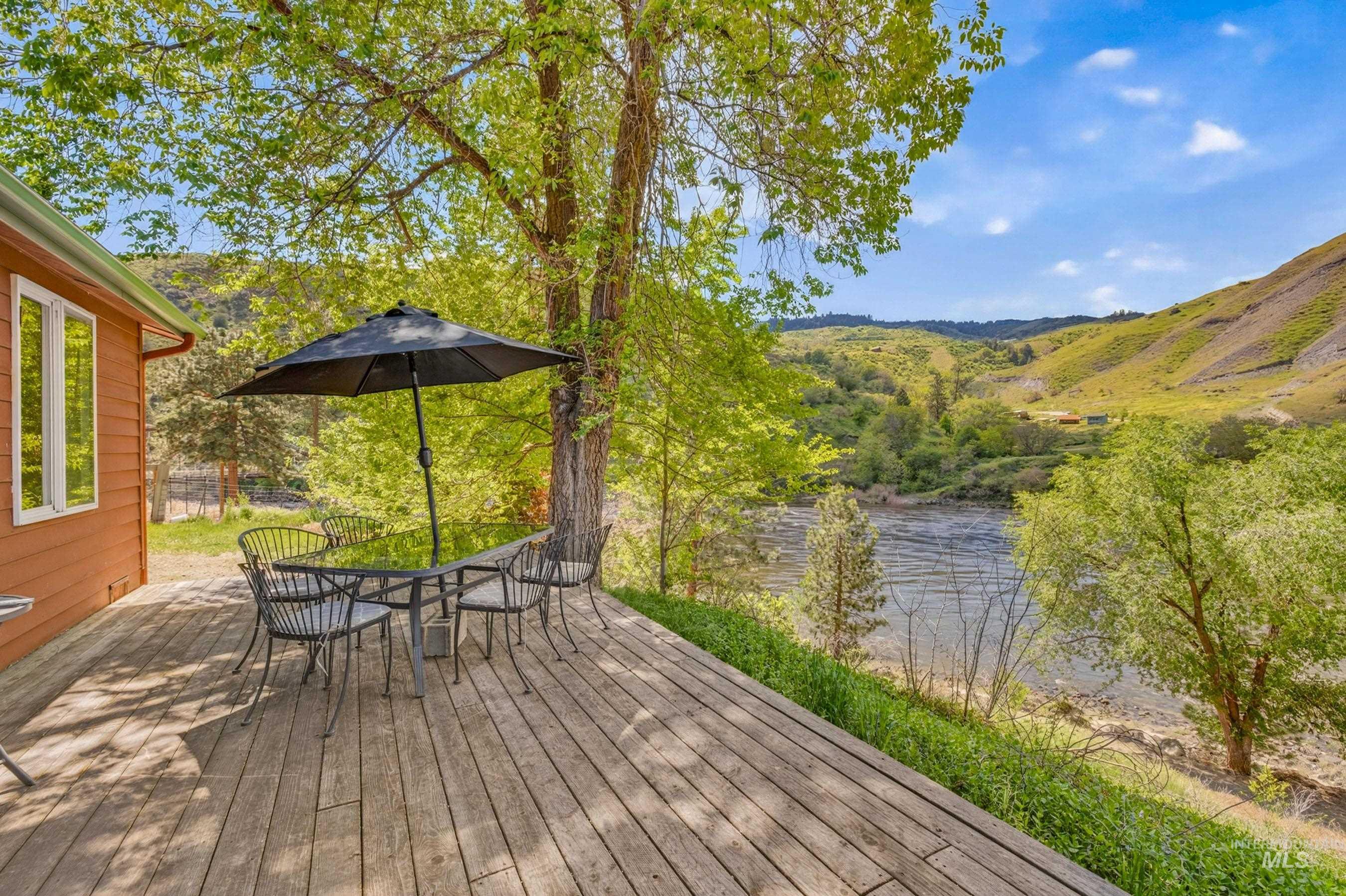 151 Cow Creek Road Lucile, ID 83542 - Photo 40 of 50 Expansive outdoor wood deck with a water frontage, surrounded by mature trees and verdant hills