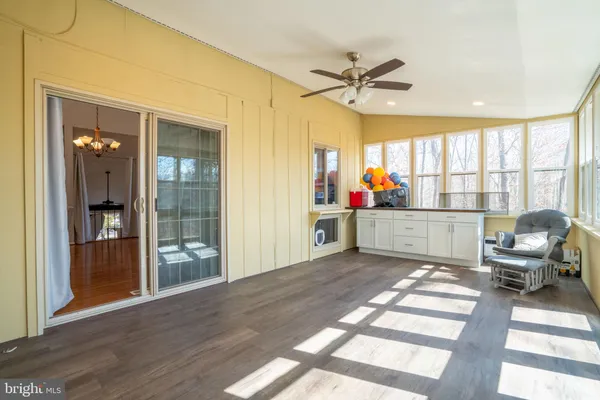 a living room with a large window wooden floor and chandelier