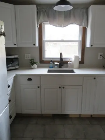 a kitchen with white cabinets a sink and dishwasher