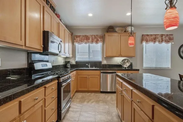 a kitchen with stainless steel appliances granite countertop a sink a stove and a refrigerator