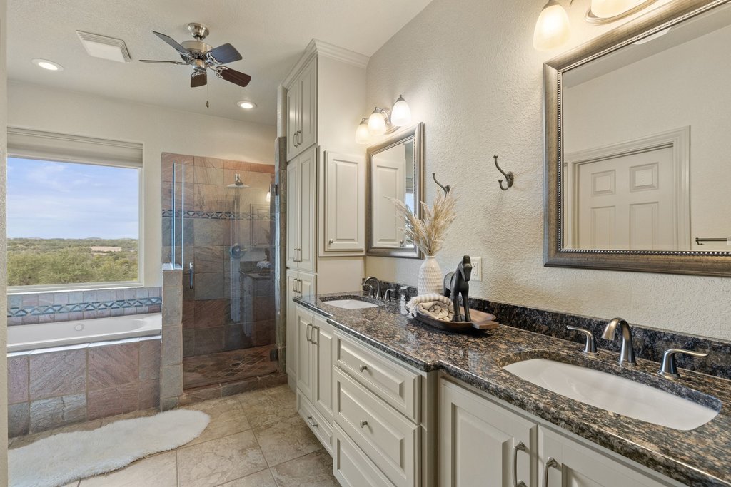 232 Crooked Oak Round Mountain, TX 78663 - Photo 19 of 40 Full bath with a garden tub, double vanity, a shower stall, a ceiling fan, and a textured wall