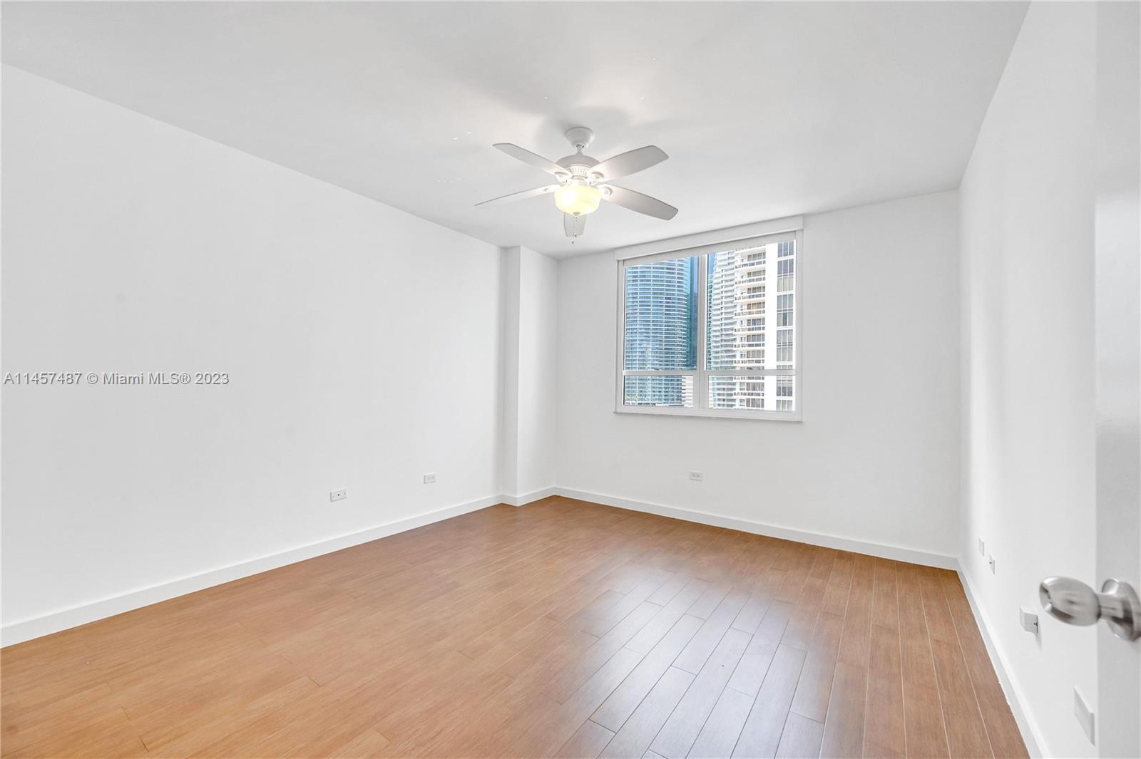 801 Brickell Key Boulevard, Unit 2208 Miami, FL 33131 - Photo 8 of 22 an empty room with wooden floor ceiling fan and windows