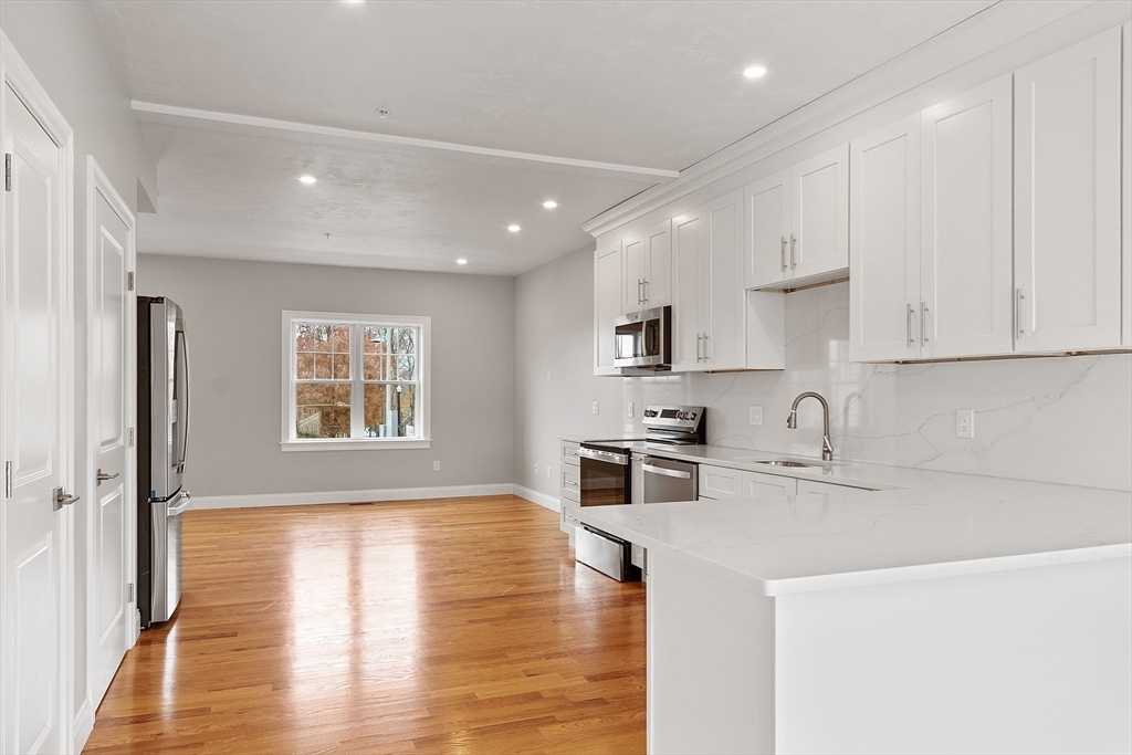 10 Windsor Street Worcester, MA 01605 - Photo 2 of 26 a kitchen with granite countertop a stove top oven a sink a refrigerator white cabinets and wooden floor next to a window
