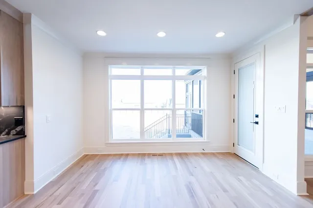 an empty room with wooden floor ceiling fan and windows