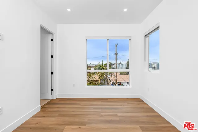 a view of an empty room with window and wooden floor