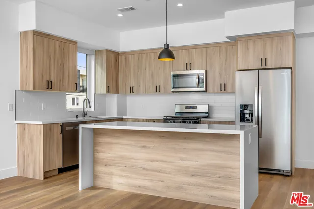 a kitchen with kitchen island white cabinets a refrigerator and a sink