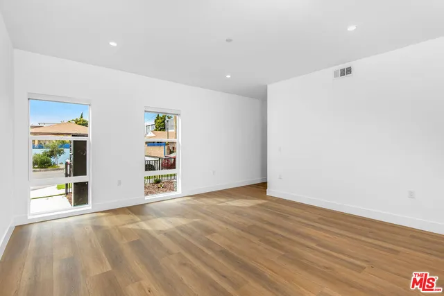 a view of a big room with wooden floor and windows